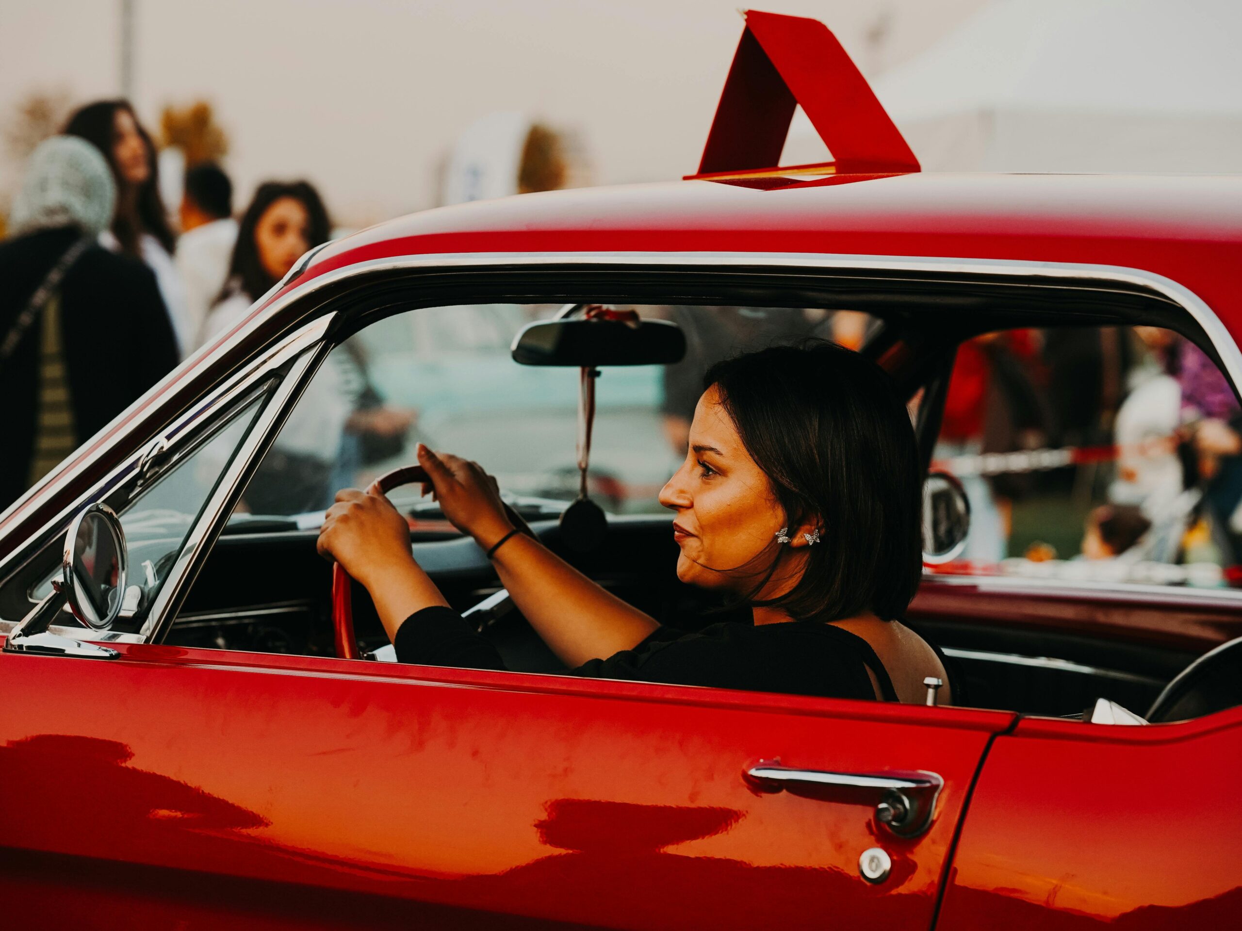 A woman driver in a red car at an outdoor event in Ankara, Türkiye.